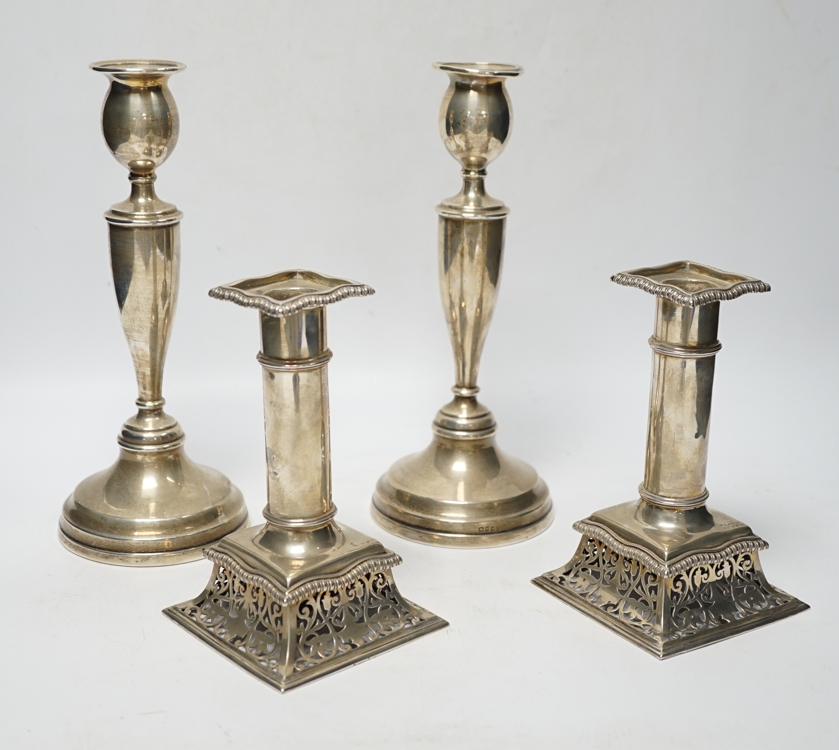 A pair of Victorian silver candlesticks, on pierced swept bases, William Leuchars, London, 1886, 15.2cm, weighted and a later taller pair of silver candlesticks.